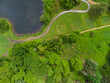 Aerial view. A large green meadow, many bushes, trees, green grass and a lake. Wilderness, no people. Beautiful nature, calm scenes. Environmentally friendly place.