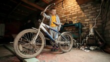 The Boy Is Going To Restore The Bike. Old-fashioned Cycle. Nostalgia. Old Rusty Bicycle. Parental Inheritance In The Garage. A Child Admires The Forgotten Vintage Bicycle. 
