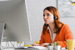 © LIGHTFIELD STUDIOS - young woman in headset typing and looking at computer monitor at home