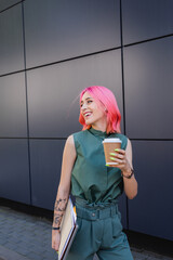 Wall Mural - smiling businesswoman with pink hair and earphone holding coffee to go and folders.