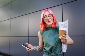 Wall Mural - happy businesswoman with pink hair and earphone holding smartphone and paper cup.