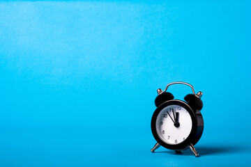 Black vintage Classic alarm clock on blue background. Time concept