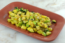 Sauteed Chopped Zucchini And Crookneck Yellow Summer Squash And Shallot Vegetable Side Dish On Red Serving Dish