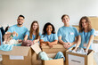 © Prostock-studio - Happy young volunteers sorting clothing donations, working together in community charity center, smiling at camera