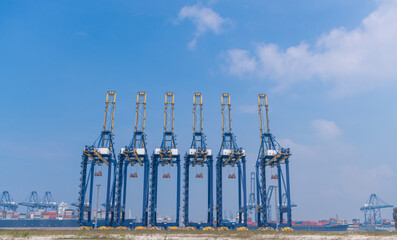 transportation logistics and container dock cargo yard and cargo plane flying with working crane bridge in shipyard with transport logistic import export with blue sky background