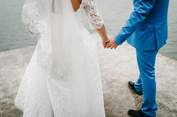 Wall Mural - Hands Close up. Bride and groom on wedding ceremony on pier. Newlyweds hold hands.