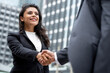 © Atstock Productions - Young smiling Hispanic businesswoman making handshake with partner in the city for greeting, dealing, merger and acquisition concepts