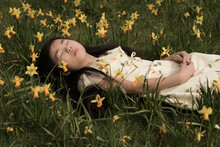 Young Asian Girl Relaxing In Field Of Daffodil Flowers In Spring
