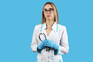 woman doctor holding stethoscope on blue background with copy space