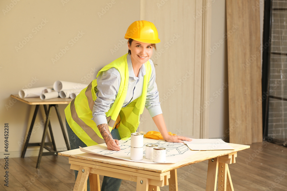 Female construction worker with house plan at table in room