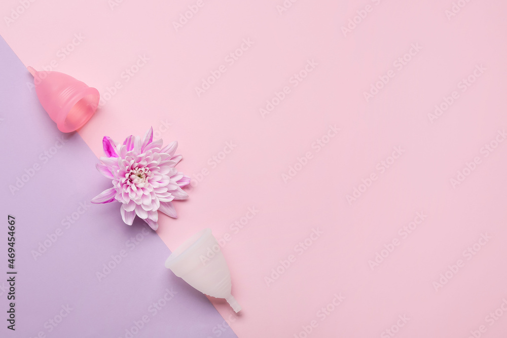 Menstrual cups and flower on color background
