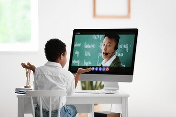 Wall Mural - Little African-American boy studying online at home