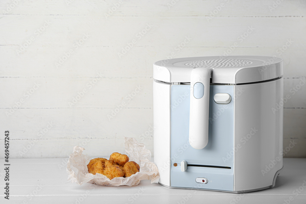 Deep fryer and delicious nuggets on table