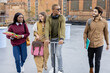 © rh2010 - Smiling multiracial students walk together at university campus. Concept of education and learning. Student lifestyle and friendship. Black man riding electric scooter. Idea of modern transportation