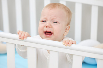 the little baby is crying in the crib, wants to sleep and milk teeth are climbing. pediatric problem