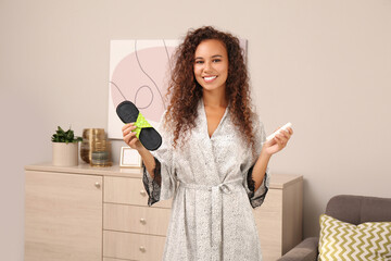 Wall Mural - Young African American woman with reusable menstrual pad and tampon at home