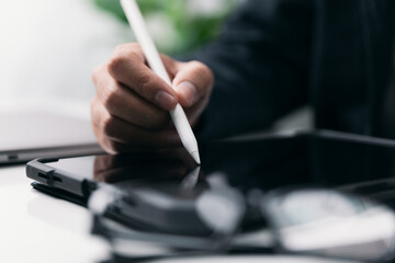 Aufkleber - Businessman working with a stylus pen on a digital tablet with a laptop computer in a modern workplace. A businessman signs a deal on his tablet using mobile apps. Concept of an electronic signature.