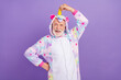 © deagreez - Photo of impressed funky man pensioner unicorn sleepwear arm hand horn smiling isolated violet color background
