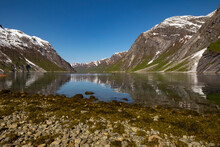 Snow Capped Mountains Reflected In The Still Waters Of The Fjord Where Kayakers Are Enjoying The View, Nordfjord, Norway, Scandinavia