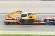 © aapsky - Trailer truck with long platform transport the Excavator on highway. Logistics of transportation of heavy and oversized cargo by road