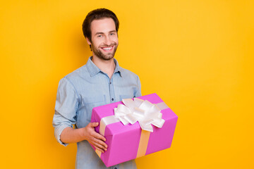 Poster - Photo of young handsome man happy positive smile hold present box party valentine day isolated over yellow color background