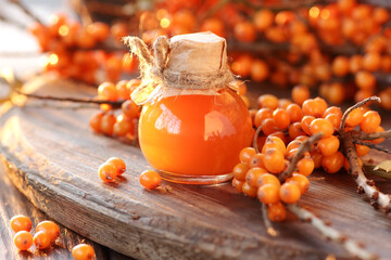 Wall Mural - Sea buckthorn oil in glass bottle with fresh berries  on wooden rustic background, closeup, natural cosmetics and naturopathy concept