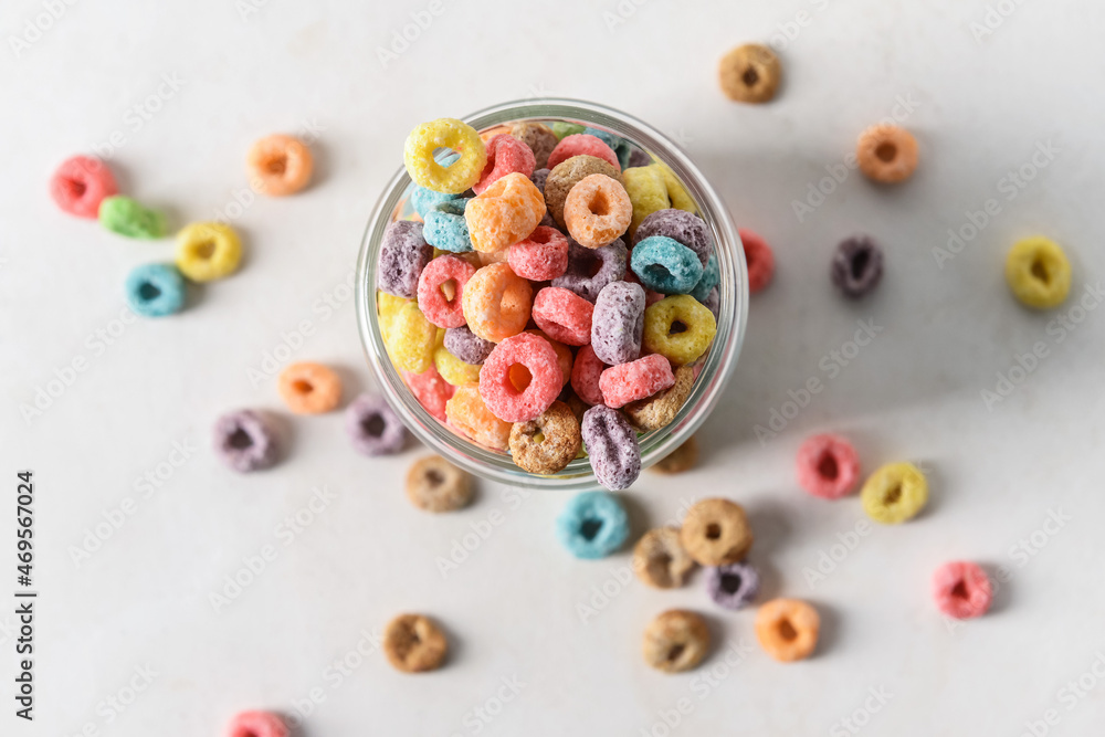 Glass with crunchy corn flakes rings on light background