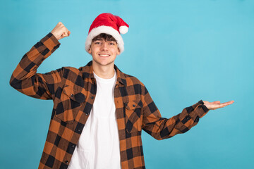 Poster - happy teenage in santa claus hat pointing at background with expression of success