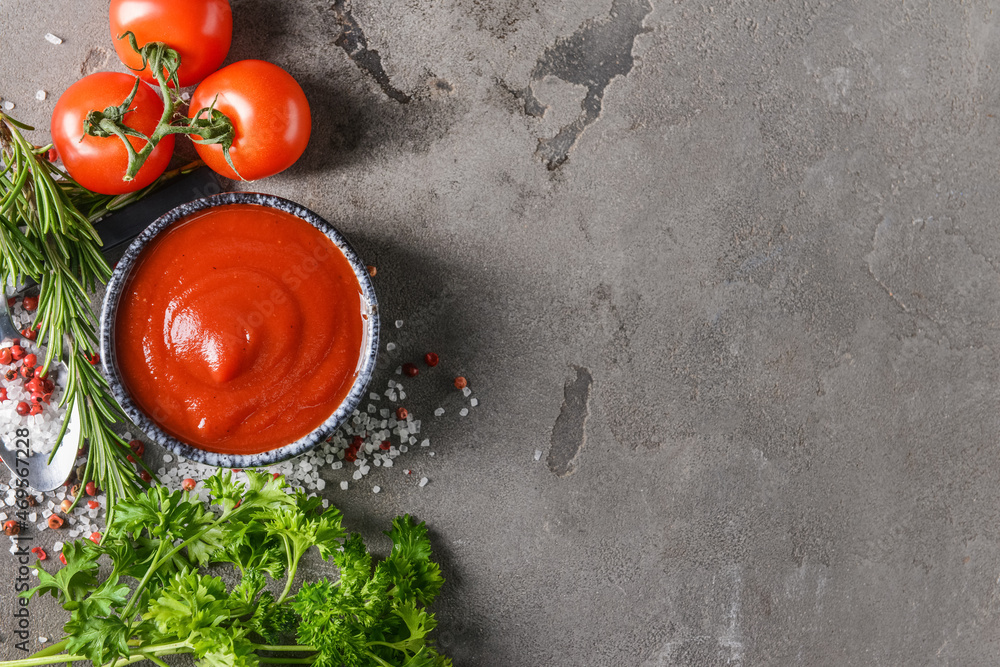 Bowl with organic tomato sauce and ingredients on grunge background