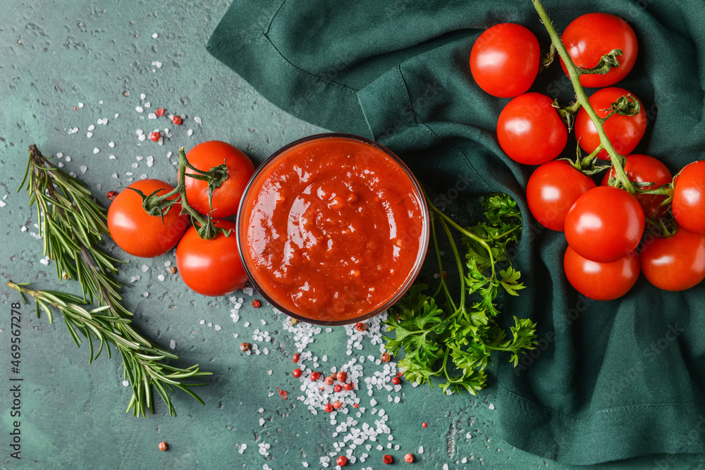 Bowl with organic tomato sauce on color background