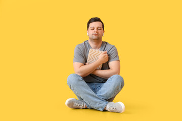 Wall Mural - Young man with book and earphones on color background