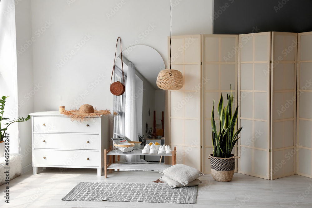 Interior of light hall with big mirror, shoes stand and folding screen
