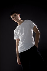 Wall Mural - Young man in white blank t-shirt posing on black background.
