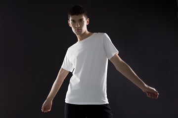 Wall Mural - Young man in white blank t-shirt posing on black background.