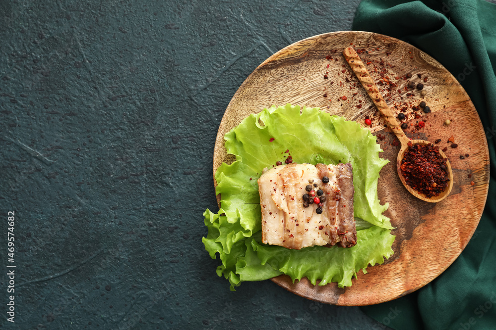 Plate with tasty bacon on black background