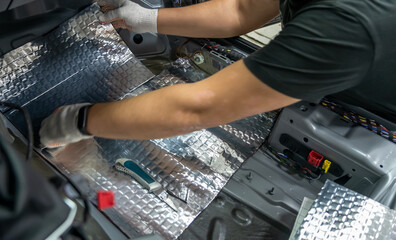 Wall Mural - Worker hands glues soundproofing material to inside of car floor. Process of car sound insulation installation.