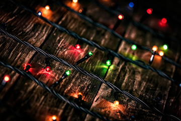 christmas garland of colorful light bulbs on an dark old weathered vintage table or wooden brown board. Christmas decoration, New Years Eve. Selective focus, bokeh, space for text.