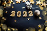 Fototapeta Mapy - Happy New Year 2022. Holiday background with golden Christmas decorations . 2022 numbers with gold jewelry balls and garland in form of stars