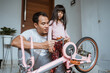 © Odua Images - Asian father tightening a bicycle pedal with his daughter