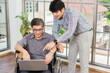 © sorapop - Asian senior disabled businessman in a wheelchair with laptop computer discuss together with team in office. Old father man sitting wheelchair and his son talking video calls conference on laptop