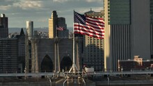 Flying Right Shot Of American Flag Atop The Brooklyn Bridge