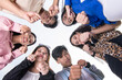 Six young asian friends huddle together, looking down and making a fight gesture with their clenched fist. A team ready for any challenge. Perspective of camera looking up.