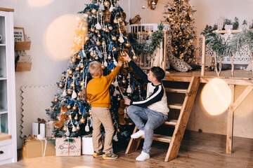 two boys are dressing christmas tree