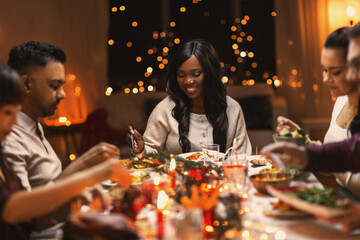 Wall Mural - holidays, party and celebration concept - multiethnic group of happy friends having christmas dinner at home