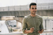 © Atstock Productions - Smiling young sweaty handsome Indian man listening to music on smartphone outdoors in the city after jogging