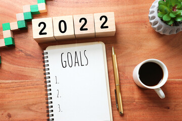 Wall Mural - Business concept of top view 2022 goals list with notebook, cup of coffee over wooden desk