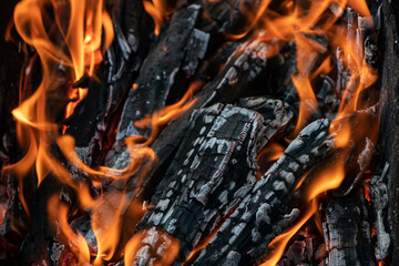 Glowing embers in hot red color, abstract background. The hot embers of burning wood log fire. Firewood burning on grill. Texture fire bonfire embers.