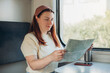 A beautiful hipster woman with map travelling on the train in Europe. Tourist travel concept.