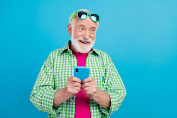 Poster - Photo of dreamy happy positive old granddad hold phone imagine comment media isolated on blue color background