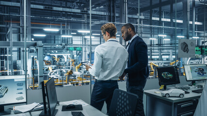 Leinwandbilder - Two Diverse Automotive Industrial Engineers Talking About Vehicle Production while Standing in Office at a Car Assembly Plant. Industrial Specialists Discuss Work Projects on Tablet Computer.